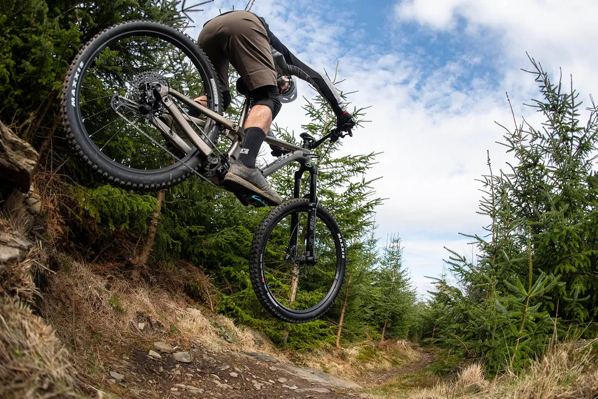 Male cyclist riding the Scott Ransom 920 full suspension mountain bike over rocky ground through woodlands