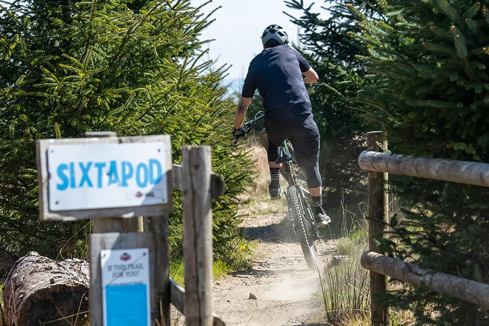 Cyclist in blue riding a full sus mountain bike at the Sixtapod Trail