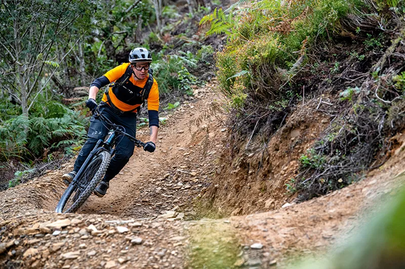 Cyclist in orange top riding the PWCA trail in Cwmcarn Forest, South Wales