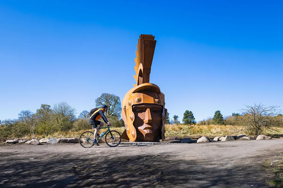 A cyclist with Silvanus, the Roman Head sculpture at Nethercroy
