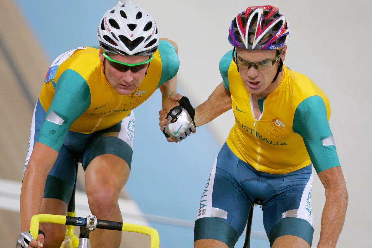 ATHENS, Greece: Australian Stuart O'Grady grabs hold of partner Graeme Brown (L) to hand-sling him foward in the men's madison final in the Olympic Velodrome at the Olympic Games in Athens, 25 August 2004. AFP PHOTO / GREG WOOD (Photo credit should read GREG WOOD/AFP via Getty Images)