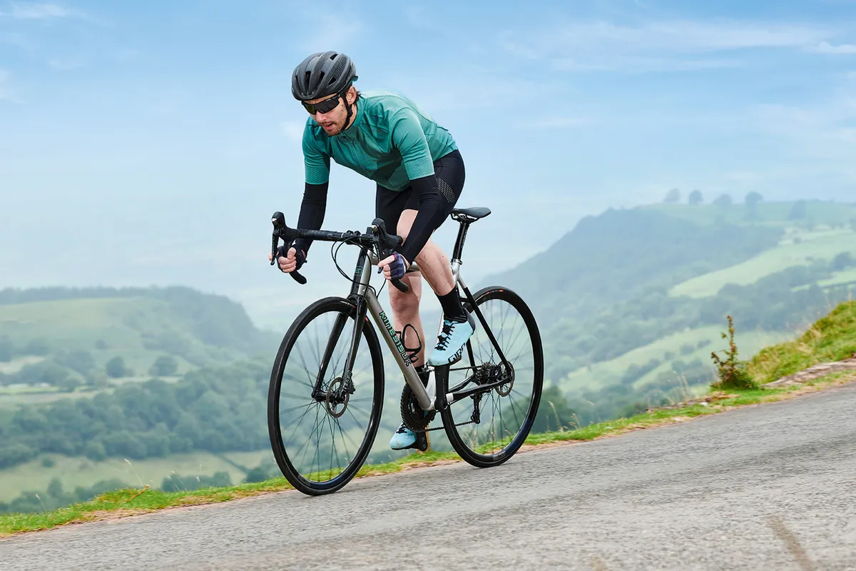 Male cyclist in green riding the Kinesis Aithen Disc road bike
