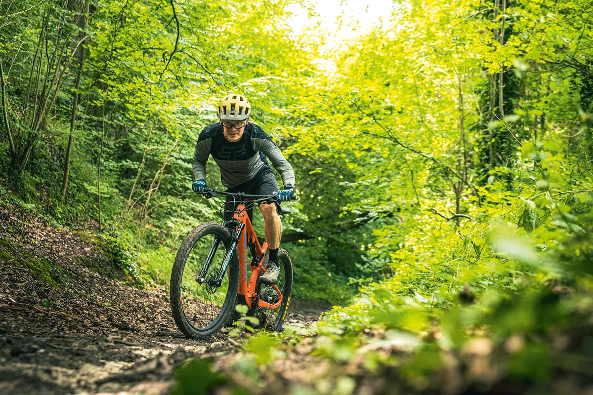 Male cyclist riding the Santa Cruz Blur XC X01 AXS RSV full suspension mountain bike through woodland