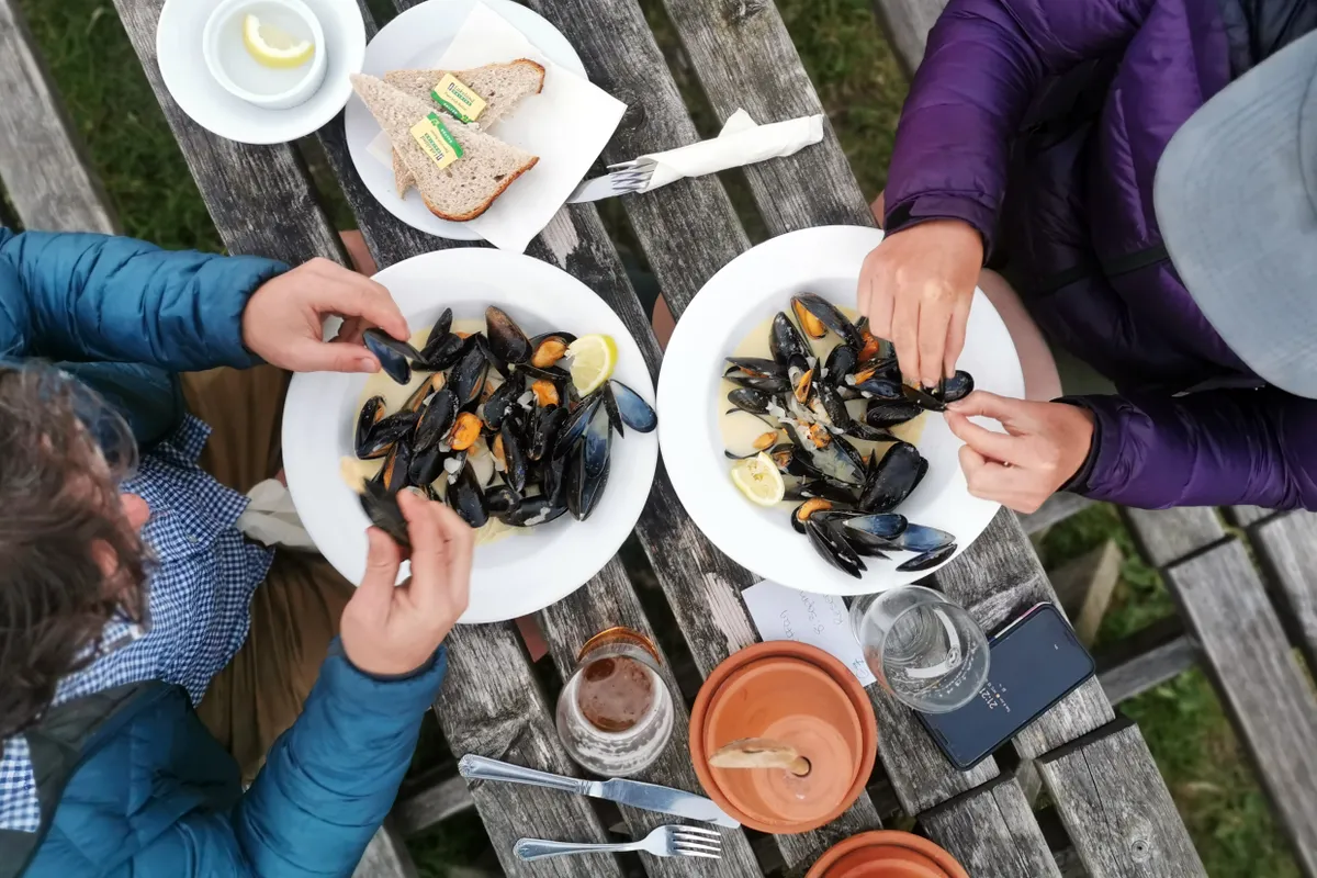 Sam Jones (Cycling UK) and Katherine Moore (Unpaved podcast) tuck into freshly caught mussels in Coverack after a day riding Cycling UK's West Kernow Way, June 2021. The 230km route is part of the EU-funded EXPERIENCE project to develop sustainable year-round tourism activities in Cornwall.