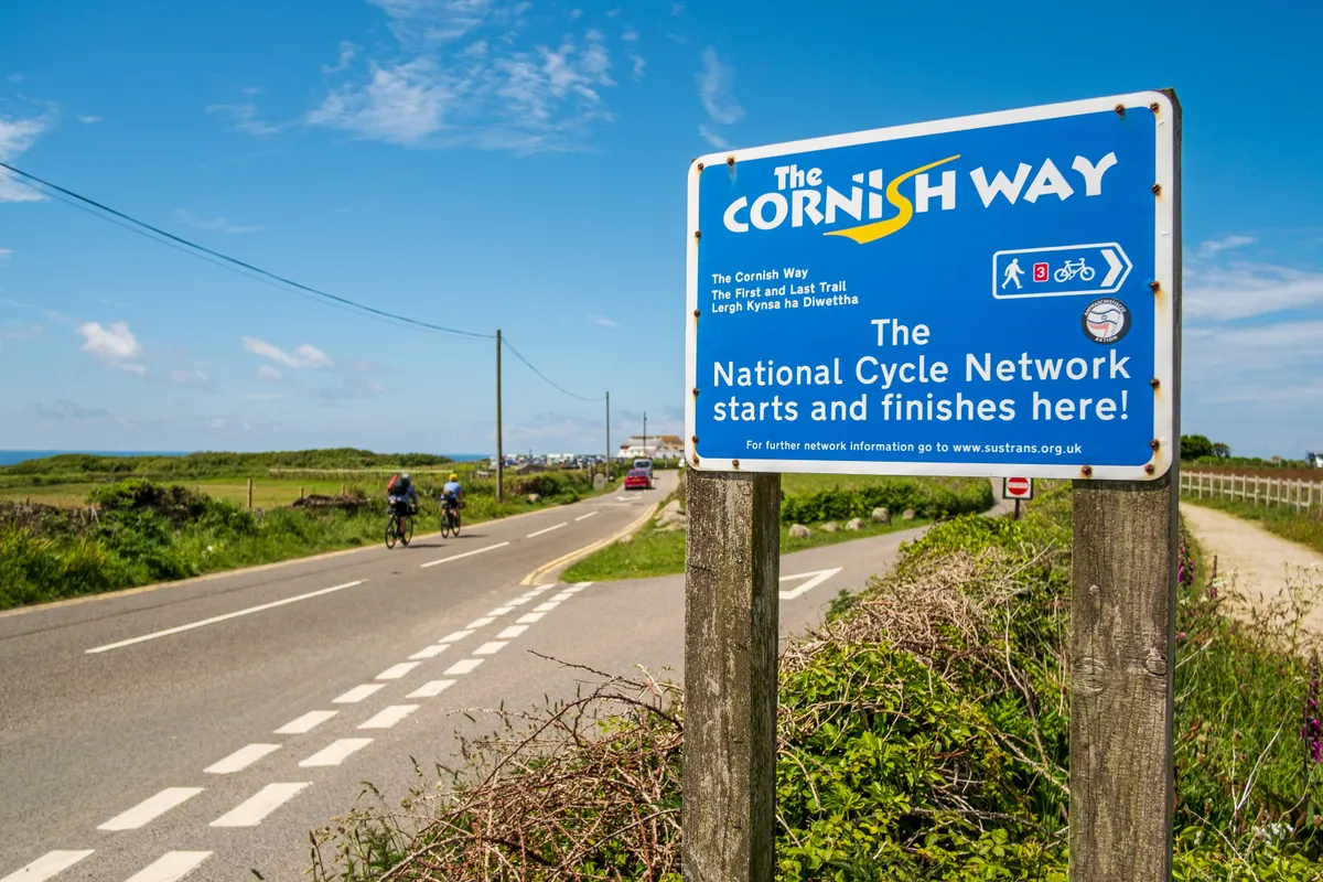 Stefan Amato (Pannier) and Katherine Moore (Unpaved podcast) reach the end of the National Cycle Network at Land's End during a recce ride of Cycling UK's West Kernow Way, June 2021. The 230km route is part of the EU-funded EXPERIENCE project to develop sustainable year-round tourism activities in Cornwall.