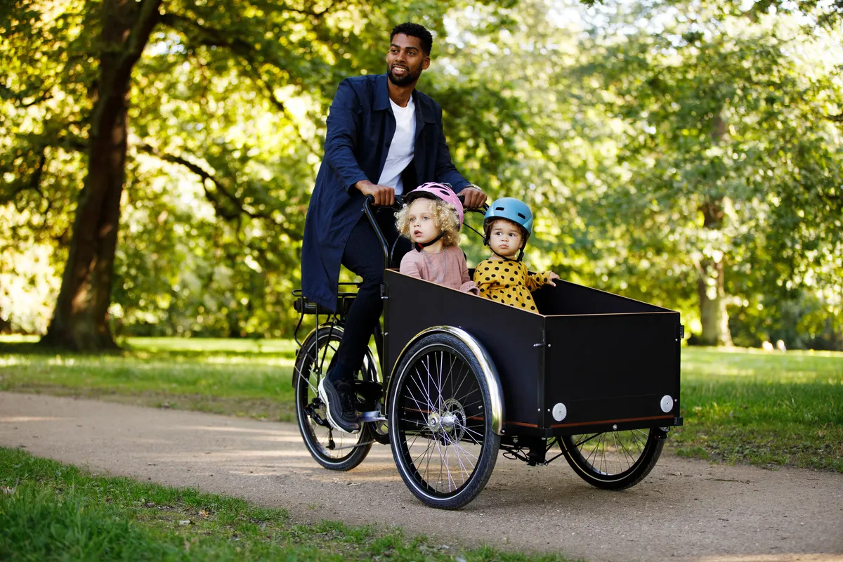Father cycling with daughters on an electric cargo bicycle