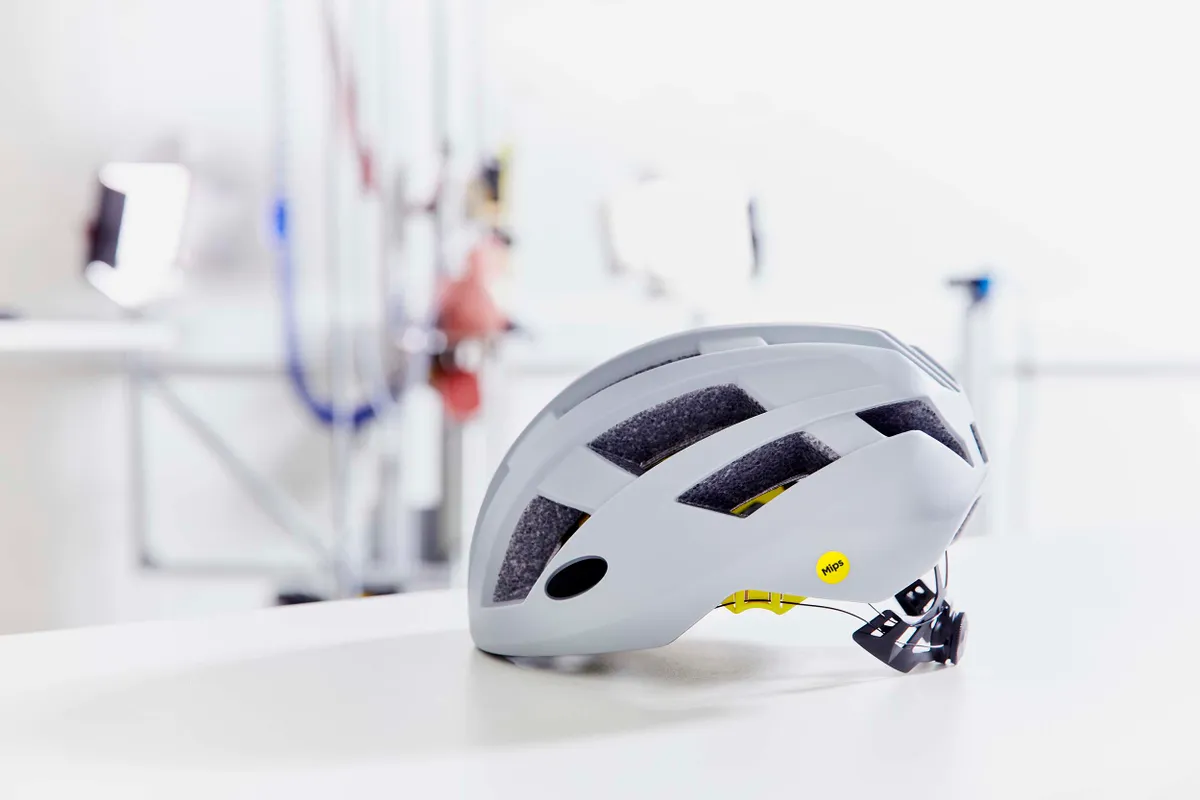 White cycling helmet on workbench with yellow MIPS logo on side