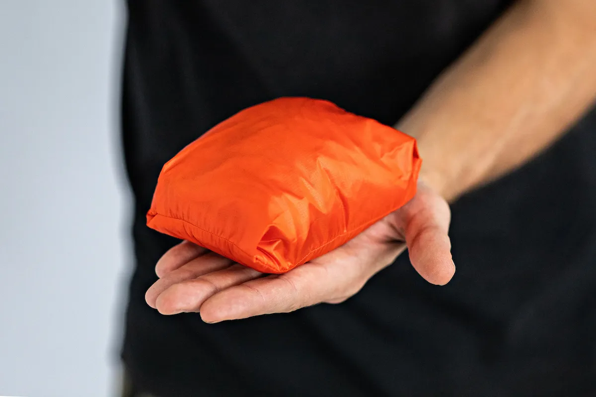 Orange Albion Zoa Burner in stuff sack on flat palm