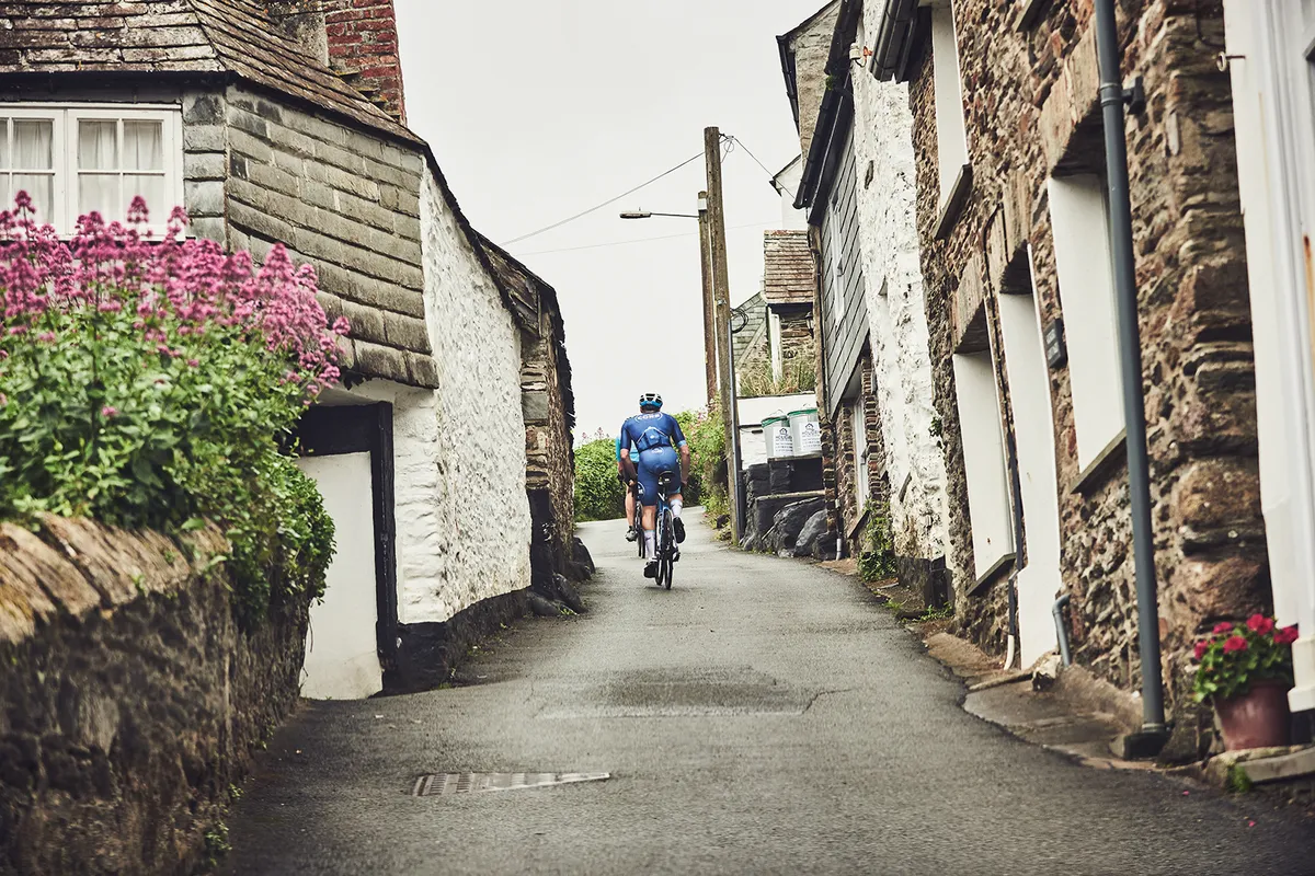 Male cyclist riding through the steep street in Cornwall