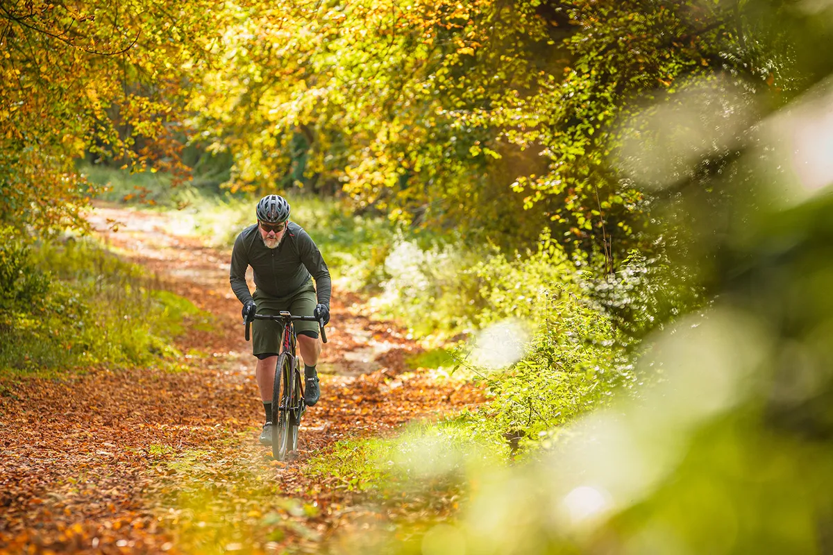 Male cyclist riding the Giant Revolt Advanced Pro 0 gravel bike through woodland