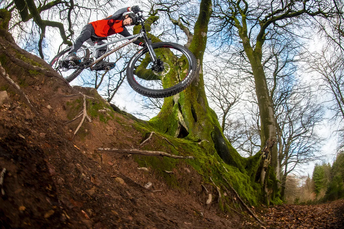 Male cyclist riding the Ribble HT 725 Pro hardtail mountain bike through woodland