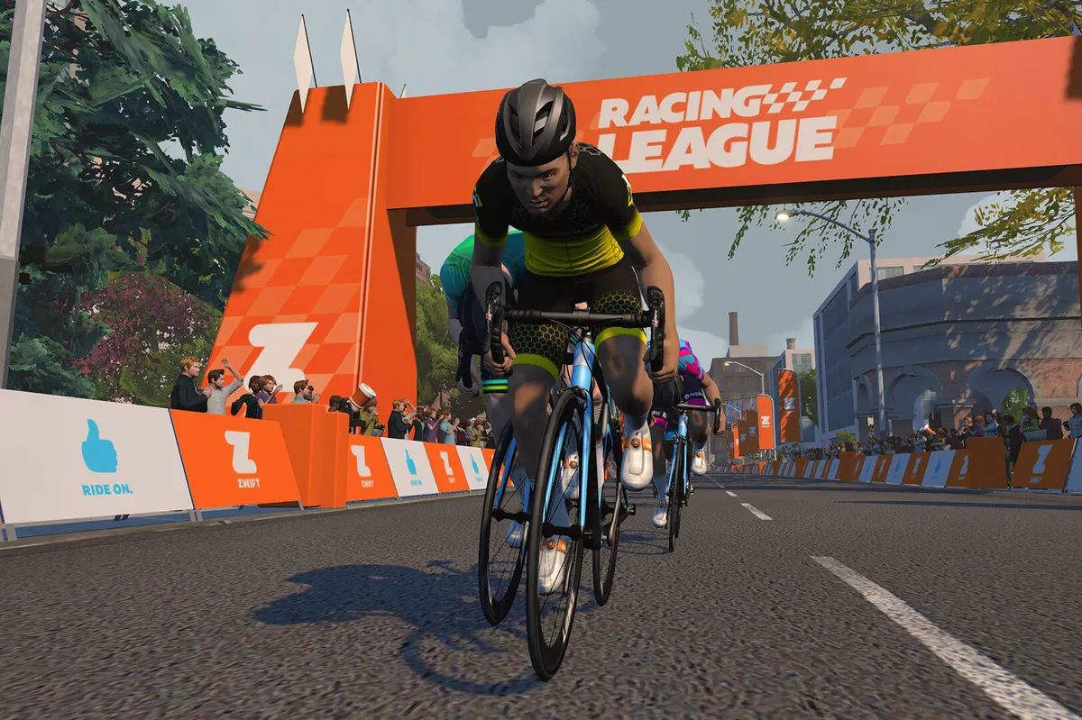 Zwift virtual racing peloton riding under a banner