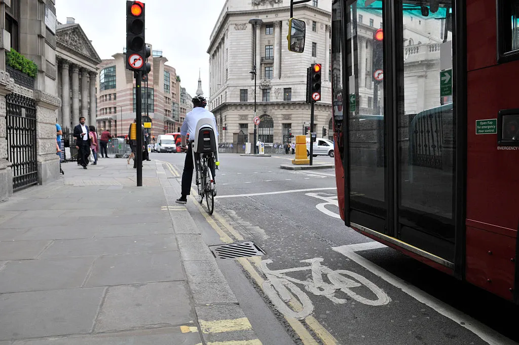 A general view of a cycle lane with a London bus and a cyclist stopped at the traffic lights on the junction at Bank near the Bank of England