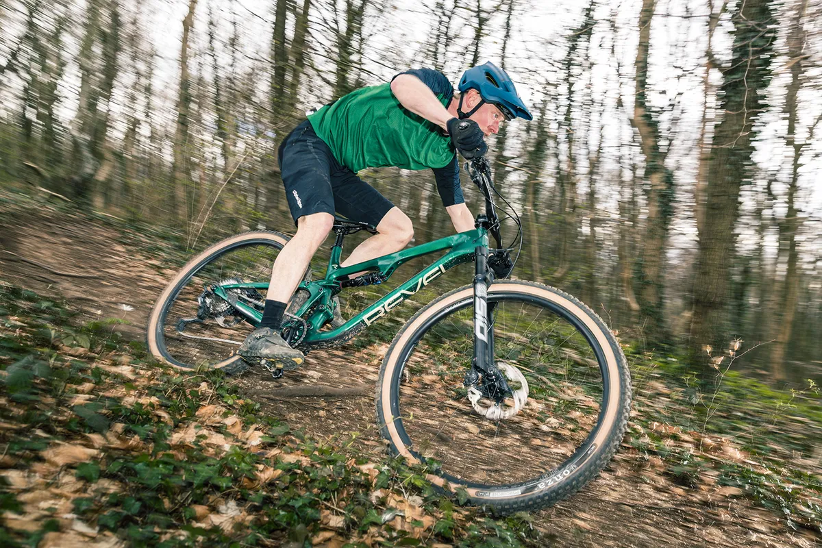 Male cyclist in green top riding the Revel Ranger 29XT full suspension mountain bike