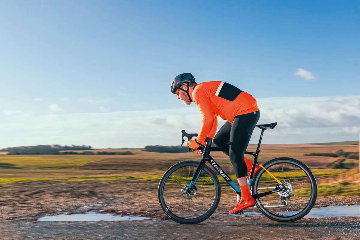 Male cyclist in orange top riding the Wilier Triestina Garda Rival AXS road bike