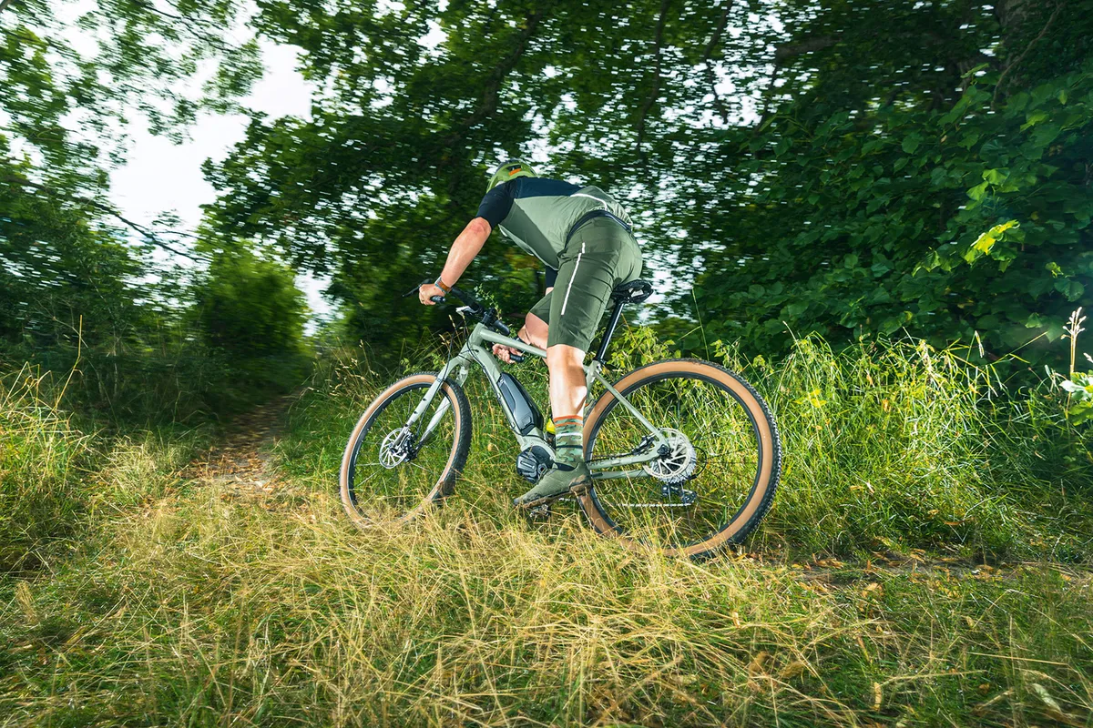 Male cyclist riding the Cairn Brave 1.0 gravel eBike through fields