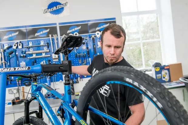 A shop mechanic working on a bike in a workstand