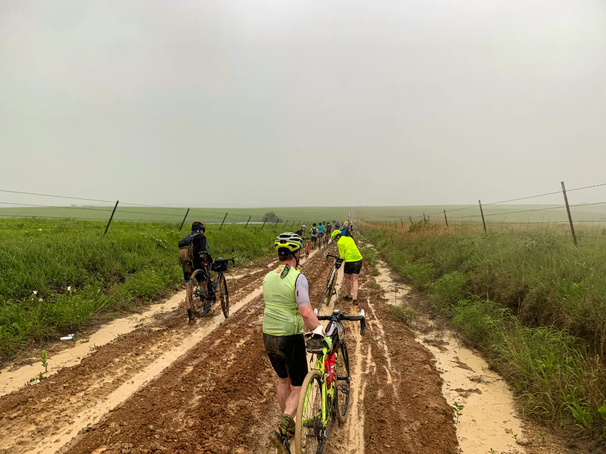 Riders walking on muddy roads during the 2022 Unbound 100 gravel race