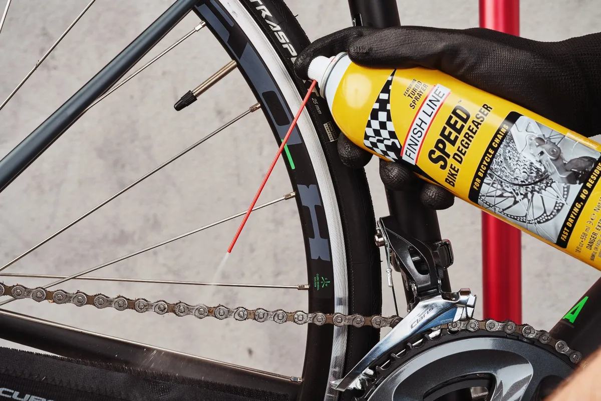 Spraying degreaser onto a bike chain