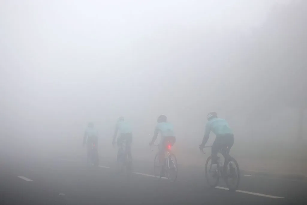 Cyclists ride along a street through dense fog in Kuwait City on January 27, 2023.