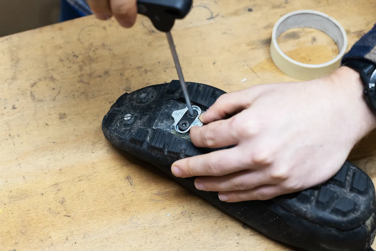 Picture showing person installing two-bolt cleat on bottom of cycling shoe.