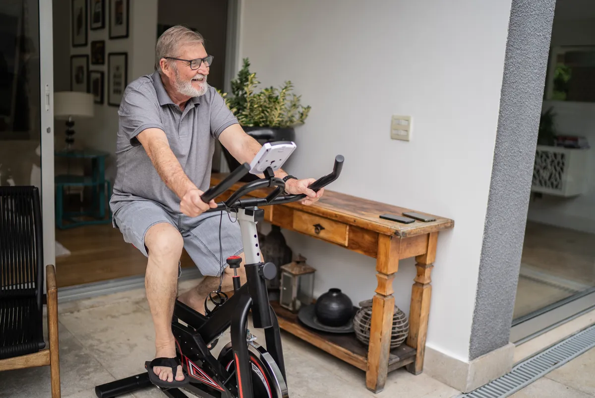 Senior man using exercise bike at home