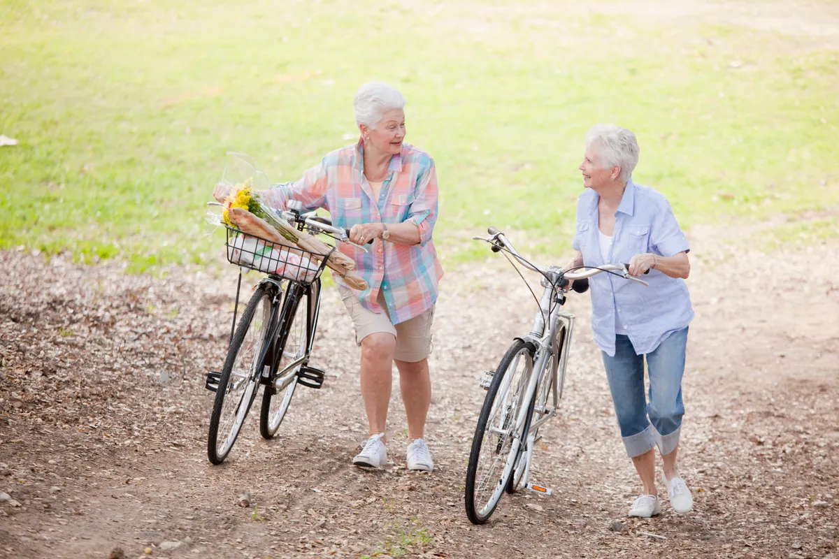 Caucasian couple walking bicycles together.
