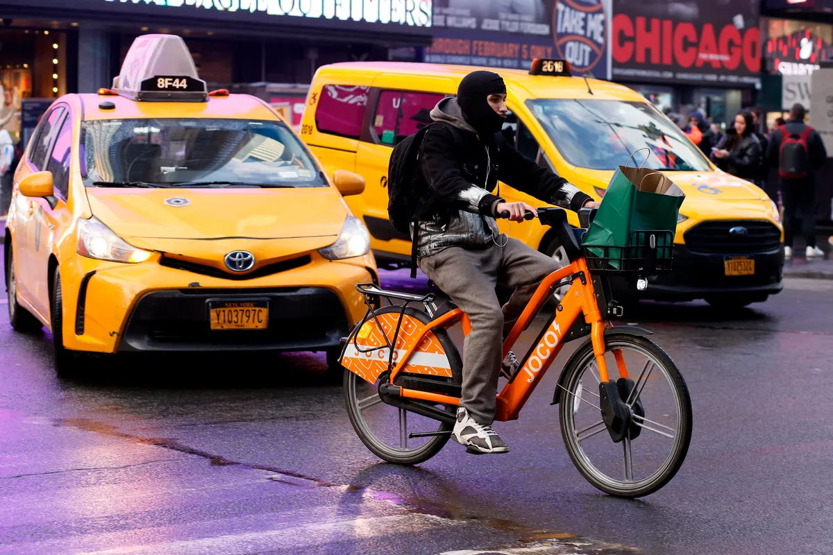 A man rides an e-bike through Times Square, New York.