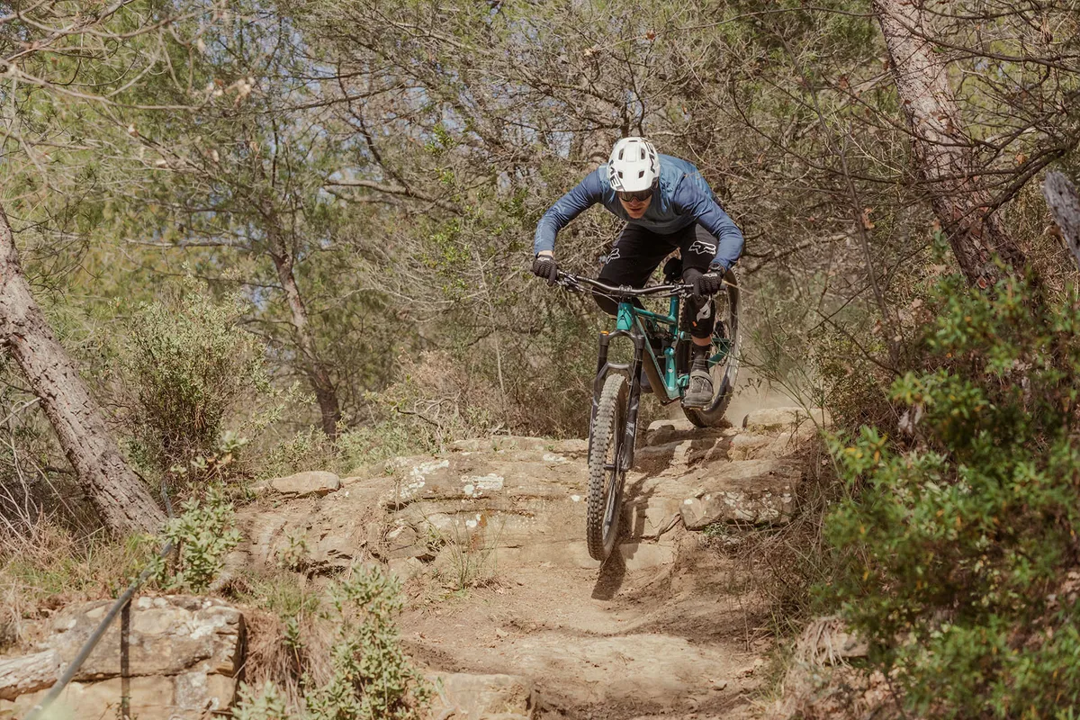 Male rider in blue top riding the Merida One-Forty 700 full suspension mountain bike