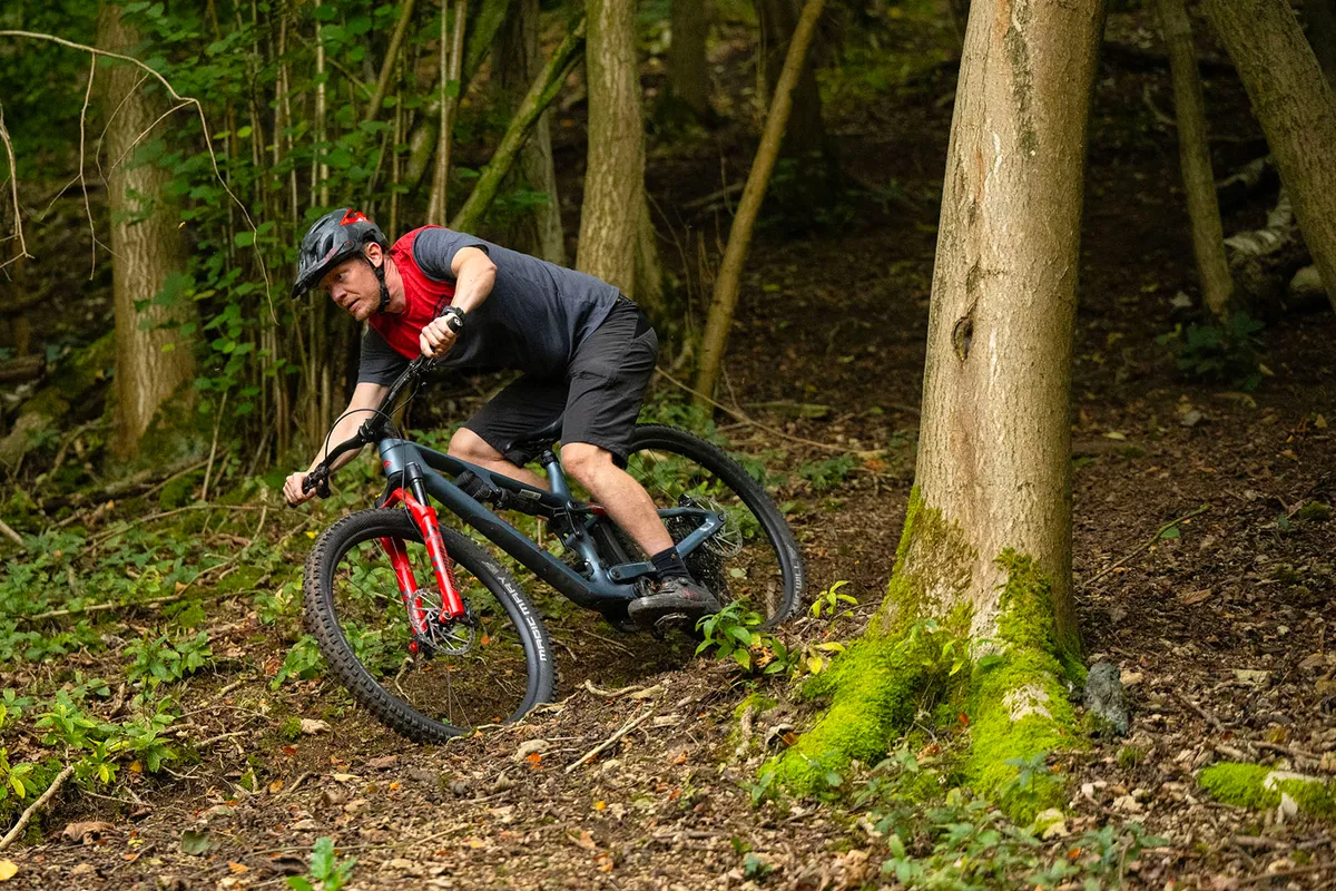 Male rider in red and grey top riding the Merida One-Forty full suspension mountain bike