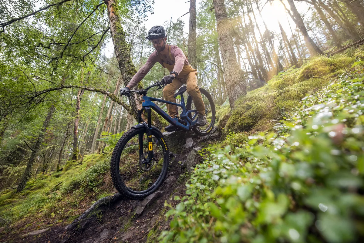 Deviate Highlander II high pivot trail mountain bike ridden by male mountain bike tester Alex Evans on a trail called Too Hard For EWS in Scotland's Tweed Valley in the UK.