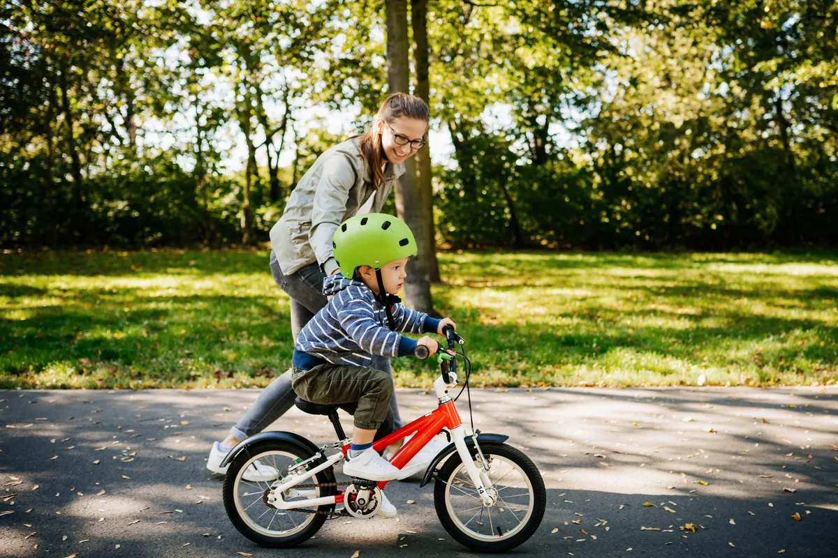 Child learning to ride his bike on a sunny afternoon in the park.