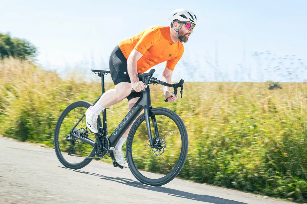 Male cyclist in orange top riding the Trek Domane  SLR 6 road eBike