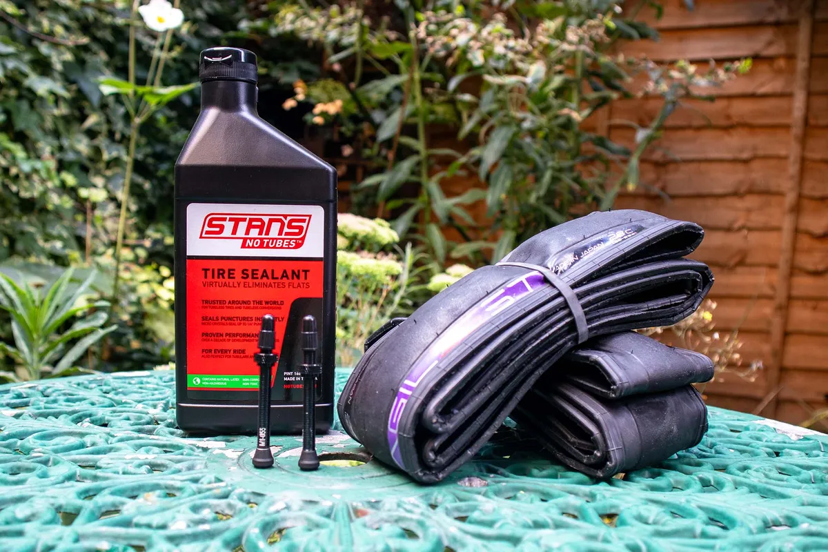 Tubeless sealant, tubeless valves and tubeless tyres on garden table.