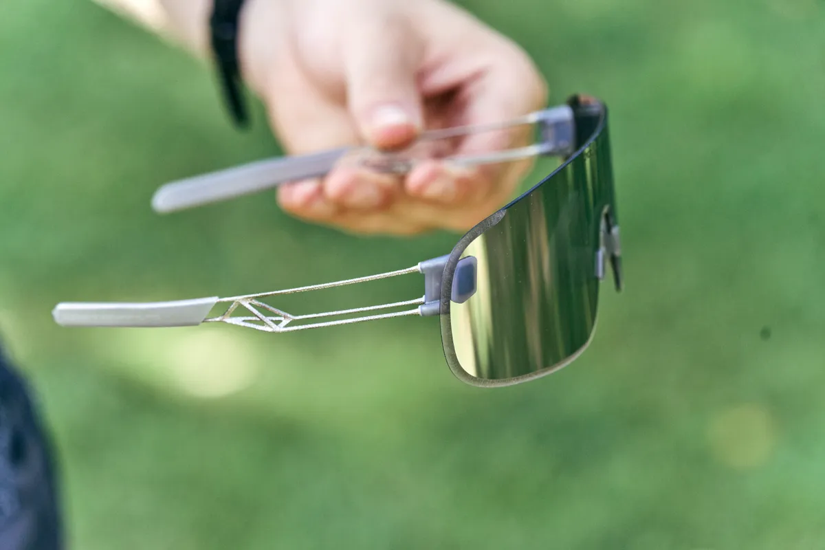 POC Elicit Ti sunglasses behind held by a cyclists' hand