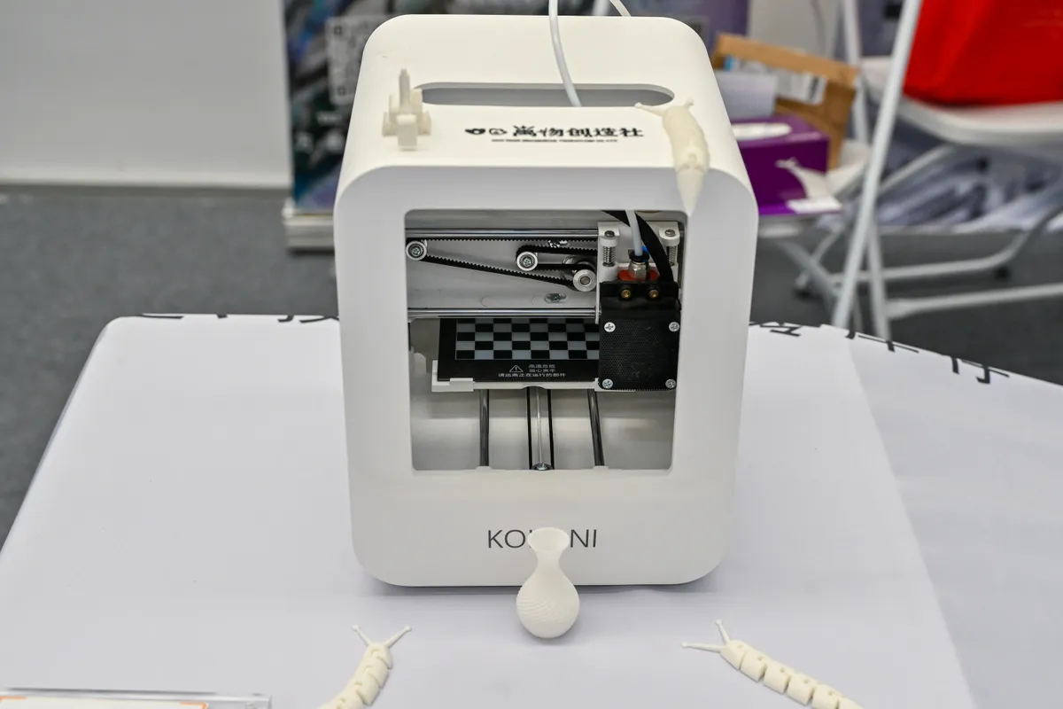 An exhibitor displays a small 3D printer at the 2023 Kunshan Yuan Universe International Equipment Exhibition