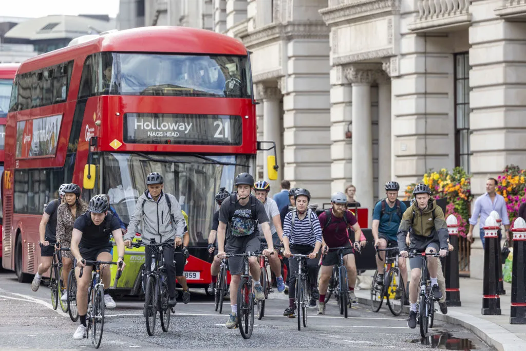 Commuters cycle in front of a bus in The City of London, UK, on Monday, Aug. 14, 2023. Average earnings excluding bonuses rose 7.3% in the year through June, only slightly less than the 7.9% rate of consumer-price inflation, Bloomberg Economics predicts ahead of official labor market data due to be published on Aug. 15. Photographer: Jason Alden/Bloomberg via Getty Images