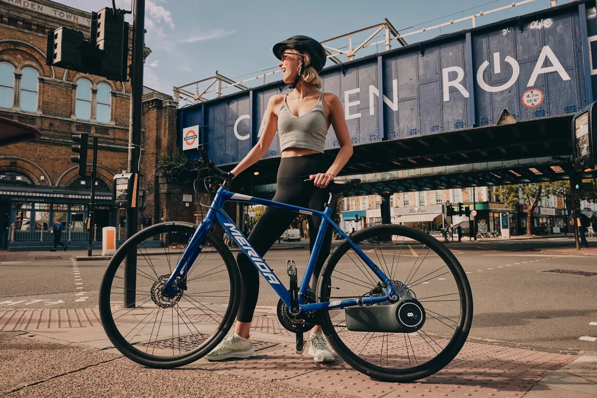 Woman posing with hybrid bike fitted with Skarper ebike unit.