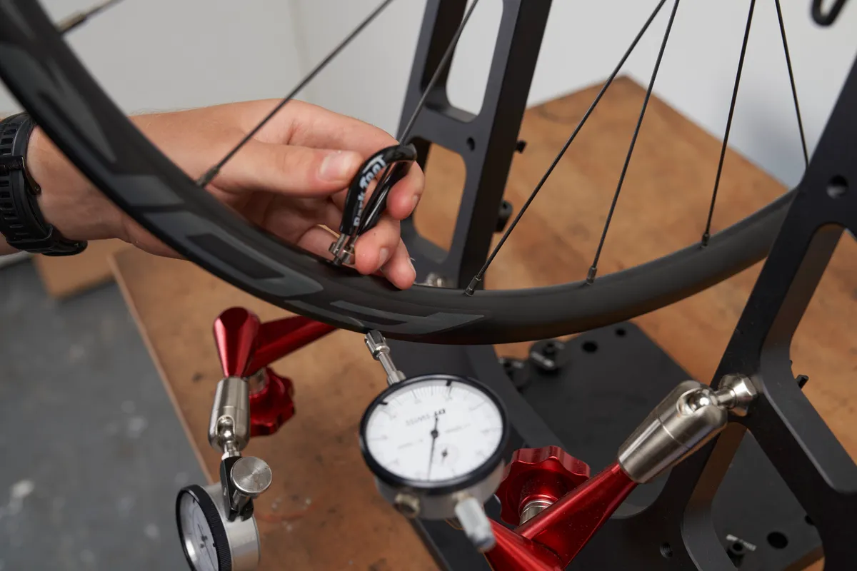 Mechanic truing wheel on wheel truing stand
