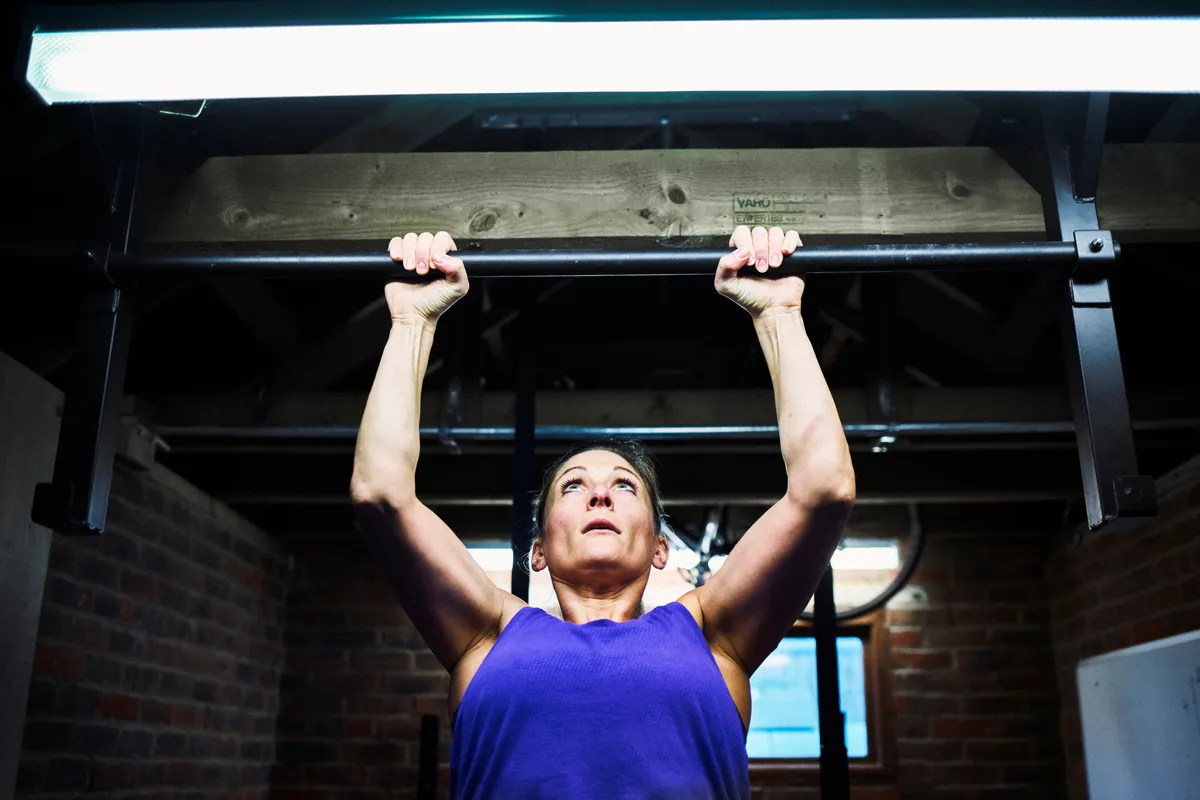 Woman exercising in custom made gym, in a small converted garage at home, specifically set up for gym exercises.