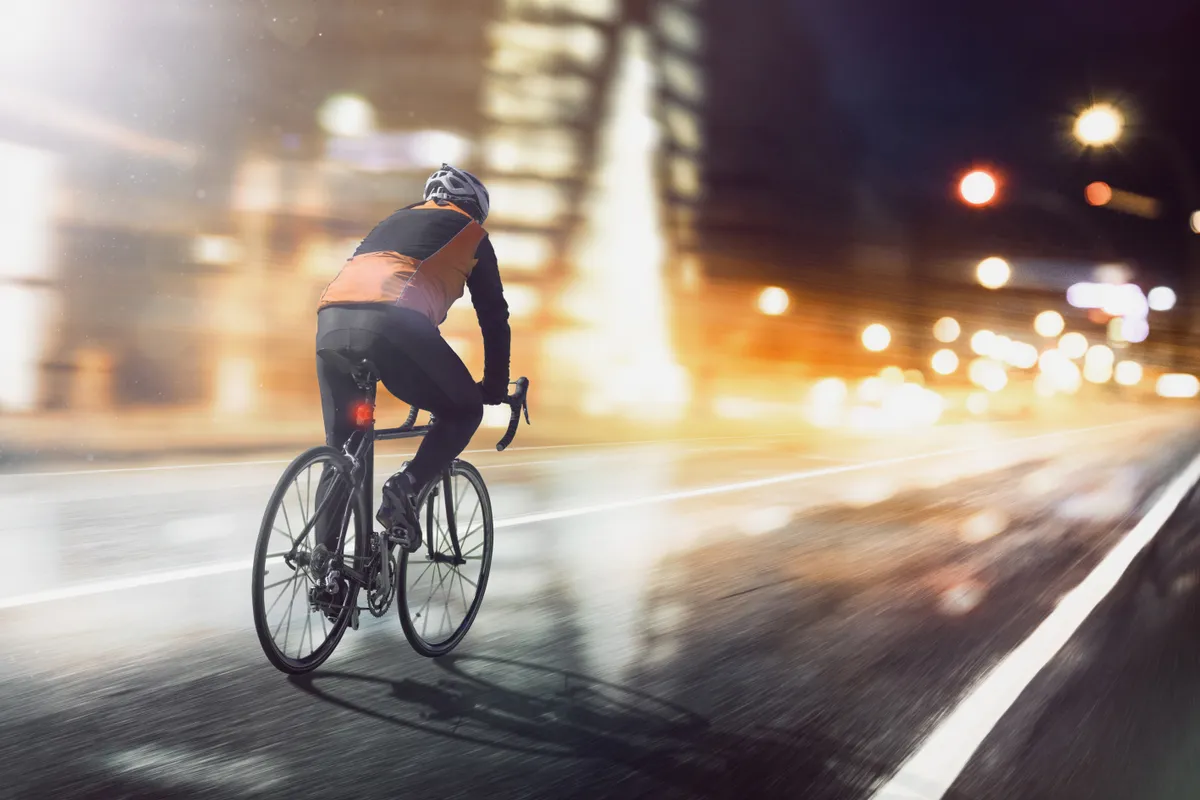 Cyclist rides through illuminated city.