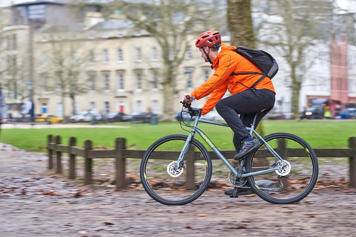 Male cyclists in orange jacket riding the Genesis Croix de Fer 10 Flat Bar commuter bike
