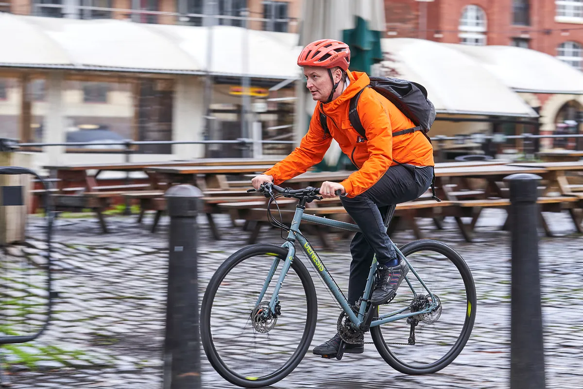 Male cyclists in orange jacket riding the Genesis Croix de Fer 10 Flat Bar commuter bike