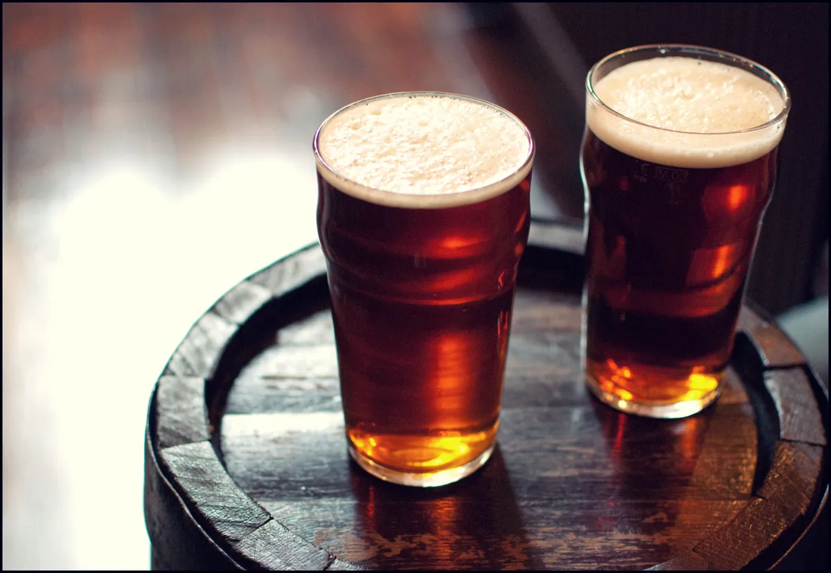 Two pints of beer bitter on wooden barrel in London pub