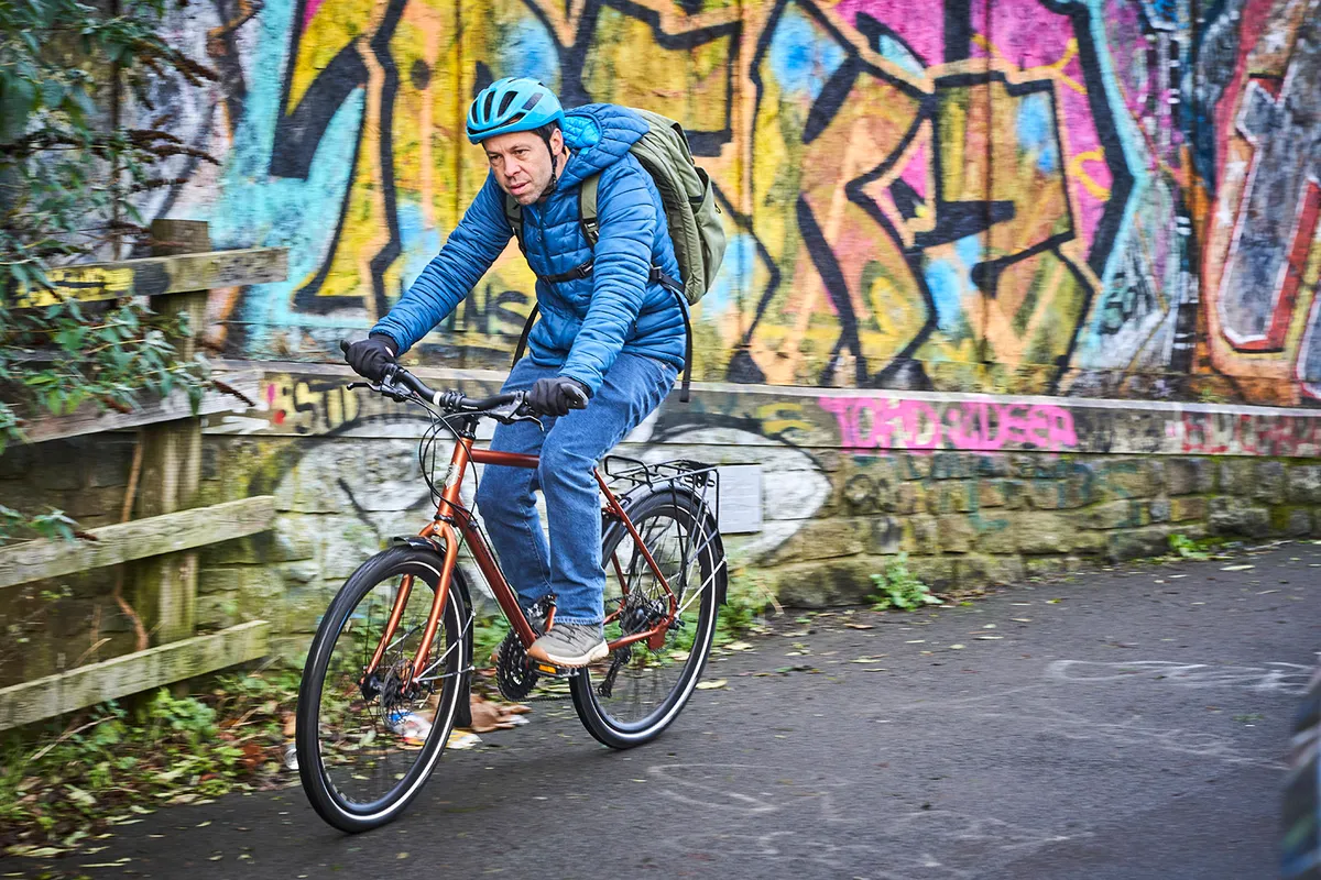 Male cyclist in a blue coat riding the Ridgeback Expedition commuter bike