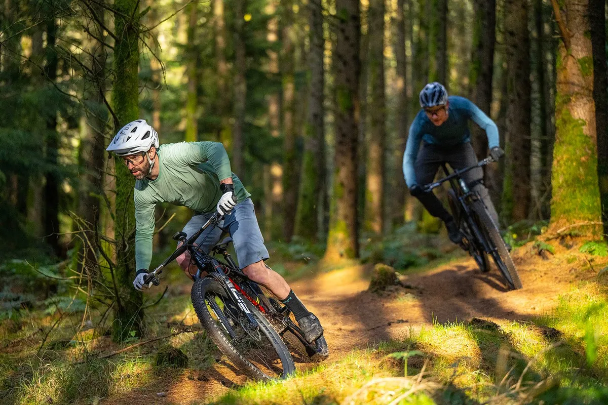Rob Weaver and Tom Marvin riding cross-country mountain bikes through woods.