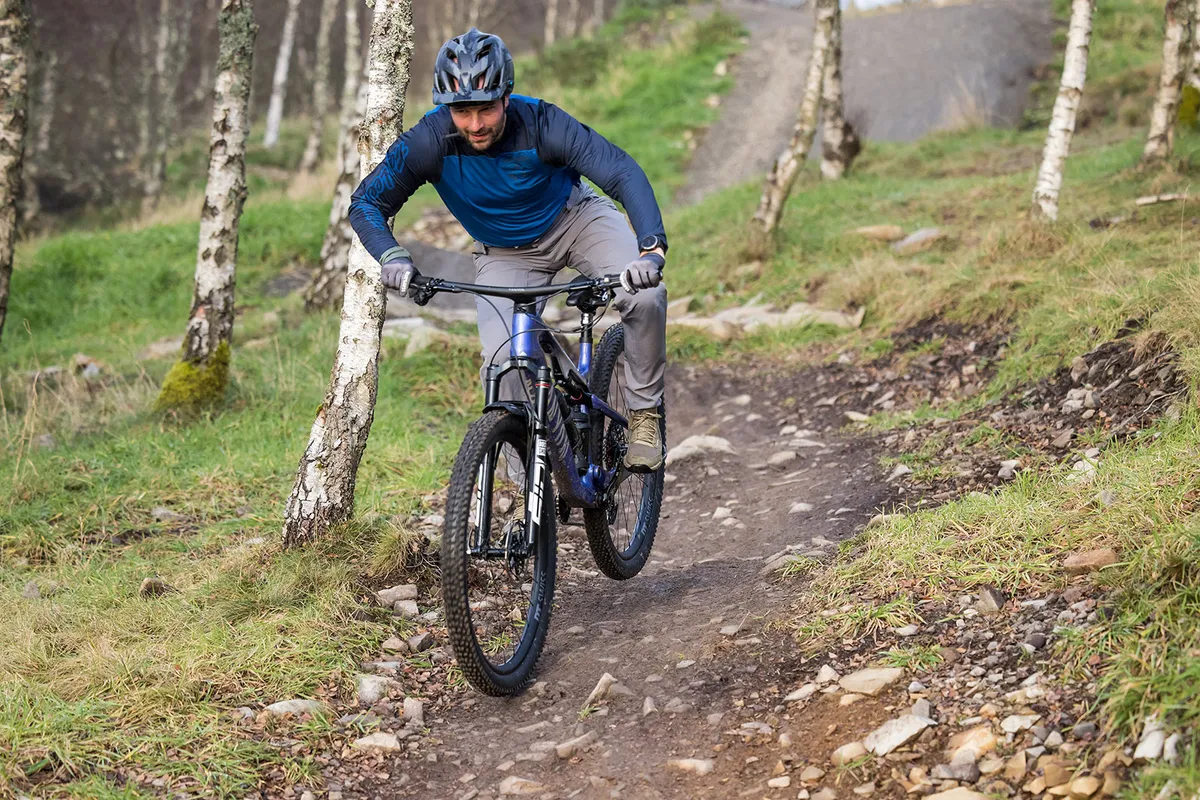 Male rider in blue top riding the Canyon Lux Trail CFR LTD downcountry full suspension mountain bike