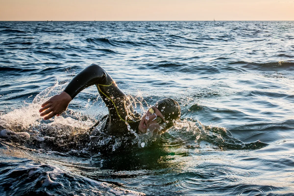 Male open water swimmer swimming forward crawl in sea.
