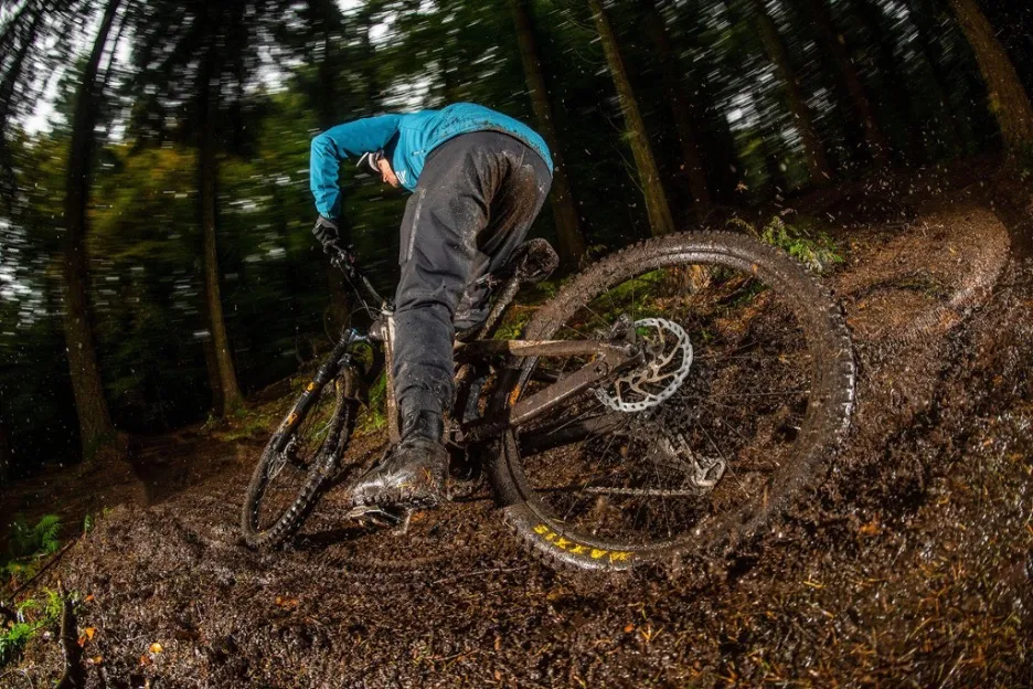 Male mountain biker riding through mud
