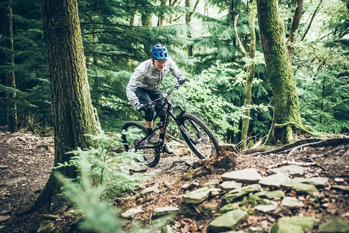 Male rider in grey top riding the Cotic Jeht Gen 2 XT Gold custom full suspension mountain bike through woodland